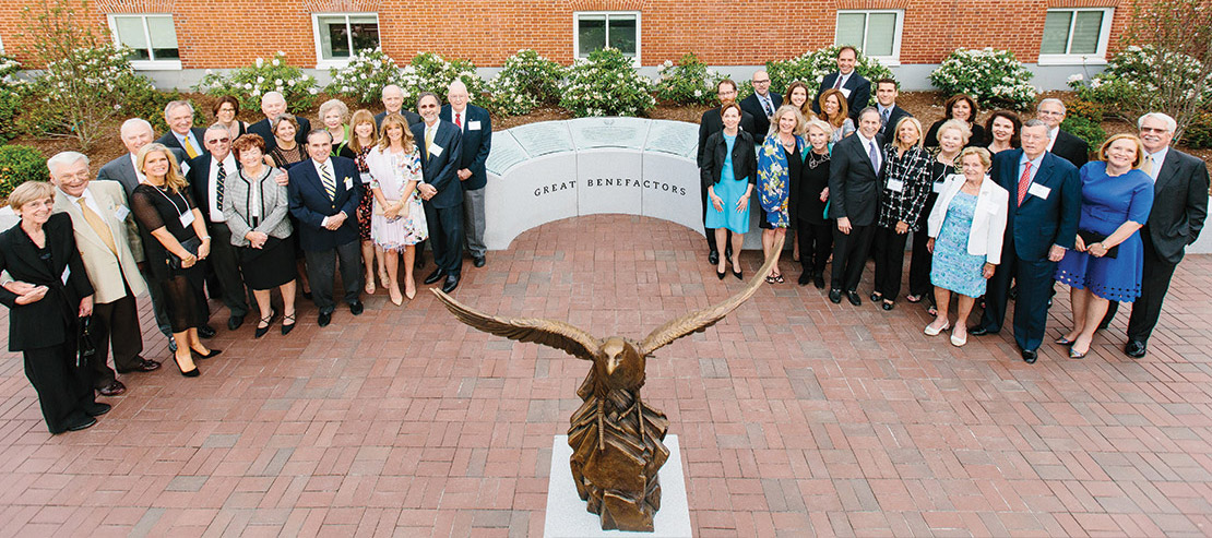 a group poses in front of the Great Benefactor's tribute