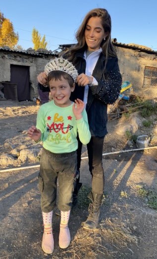 Kristina Ayanian ’19 places her Miss Universe Armenia crown on the head of a smiling young Armenian girl. The girl and her family are Artsakh refugees.