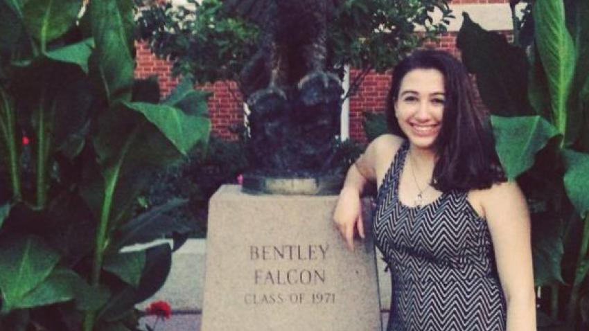 bentley honors student amanda pine stands next to the falcon statue at bentley