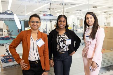 Three Bentley students — Lakshmi Narayanan, Franchesca Vilmenay and Sushmita Tandale — pose outside of a glass-walled laboratory at Boston Scientific's global headquarters in Marlborough, Massachusetts.