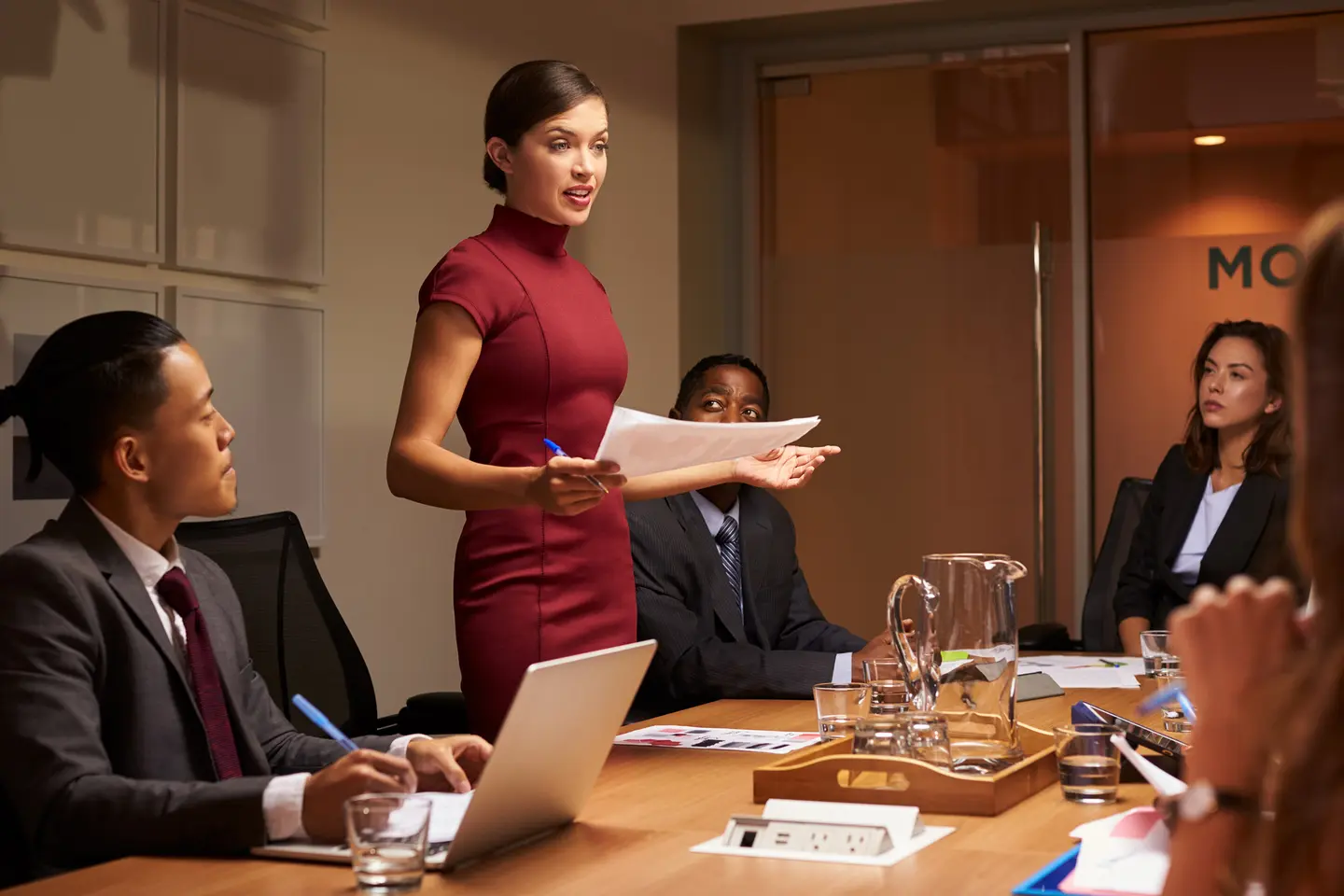 Professional woman in business attire delivering a presentation to a group of listeners