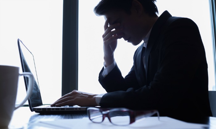 Stressed man looking at laptop