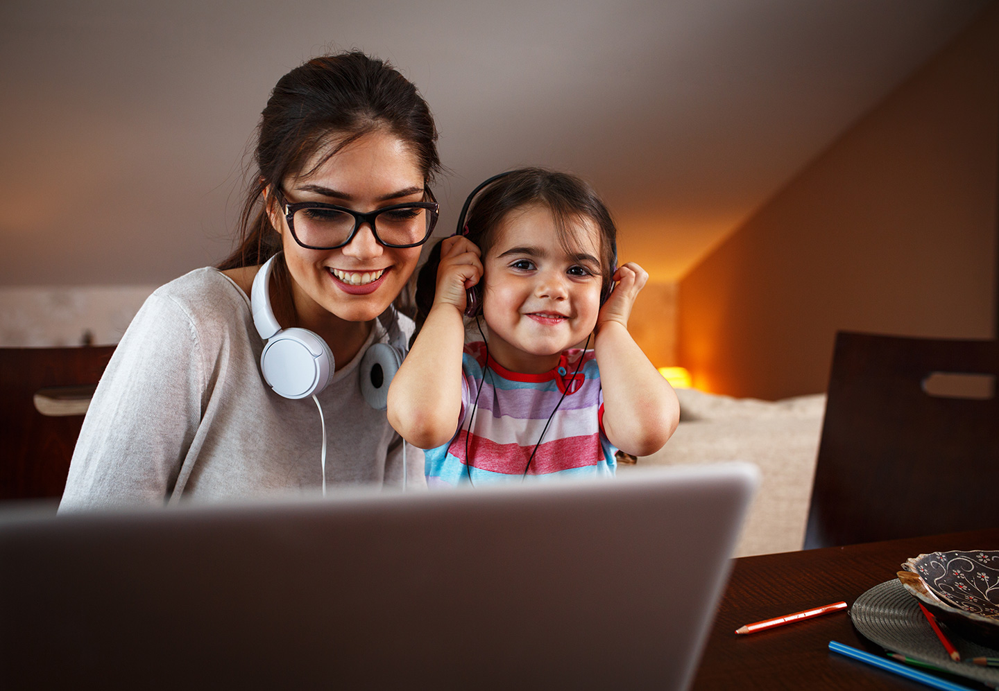 Woman at computer screen learning next to her young daughter