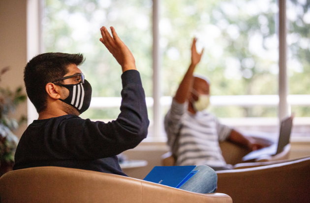 Students in classroom with raised hands