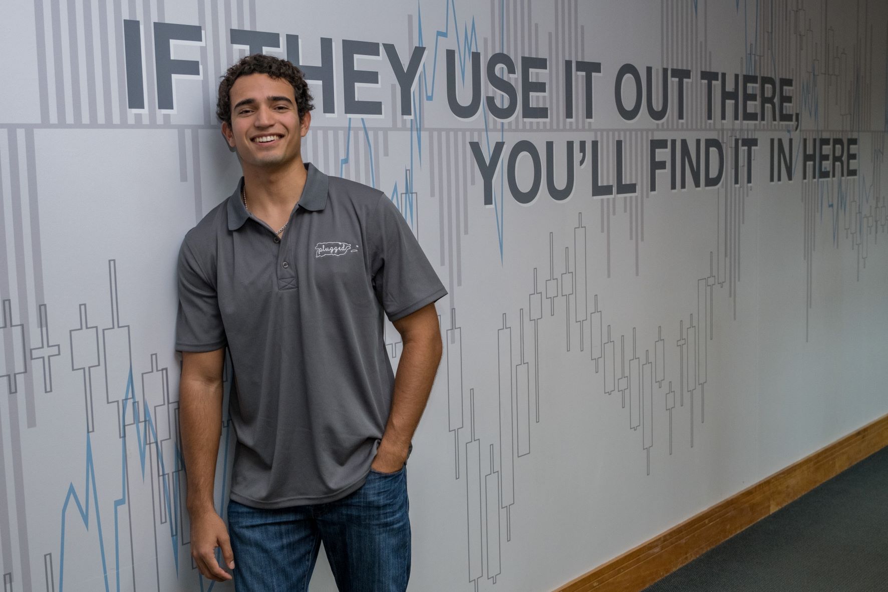 Bentley student Gabriel San Miguel leaning against wall and smiling
