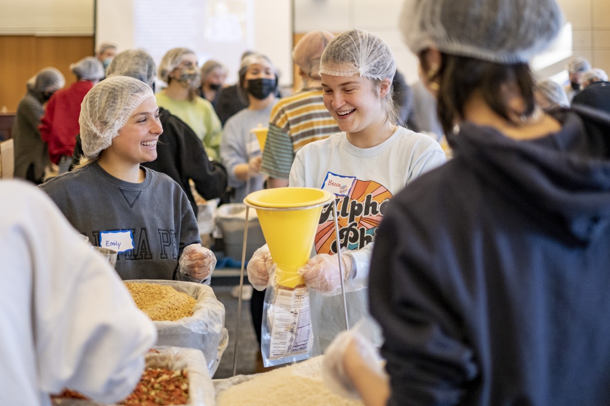 Two female Bentley students package meals during the Interfaith Council's annual Day of Service.