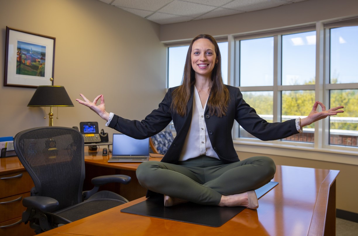 Bentley graduate sitting on the top of desk in lotus position