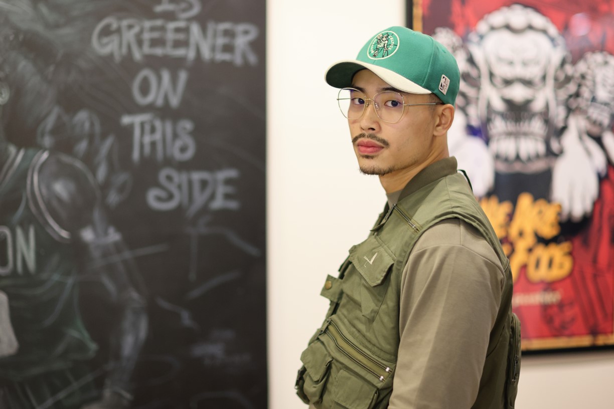 Bentley alumnus Jonathan Yu stands in front of two of his artworks on display in the Bentley Library's RSM Art Gallery