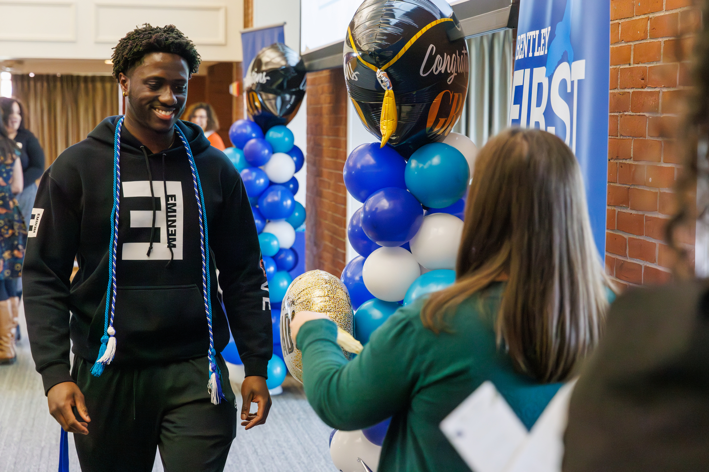 First-Gen Student walking across a stage to receive a cord for graduation