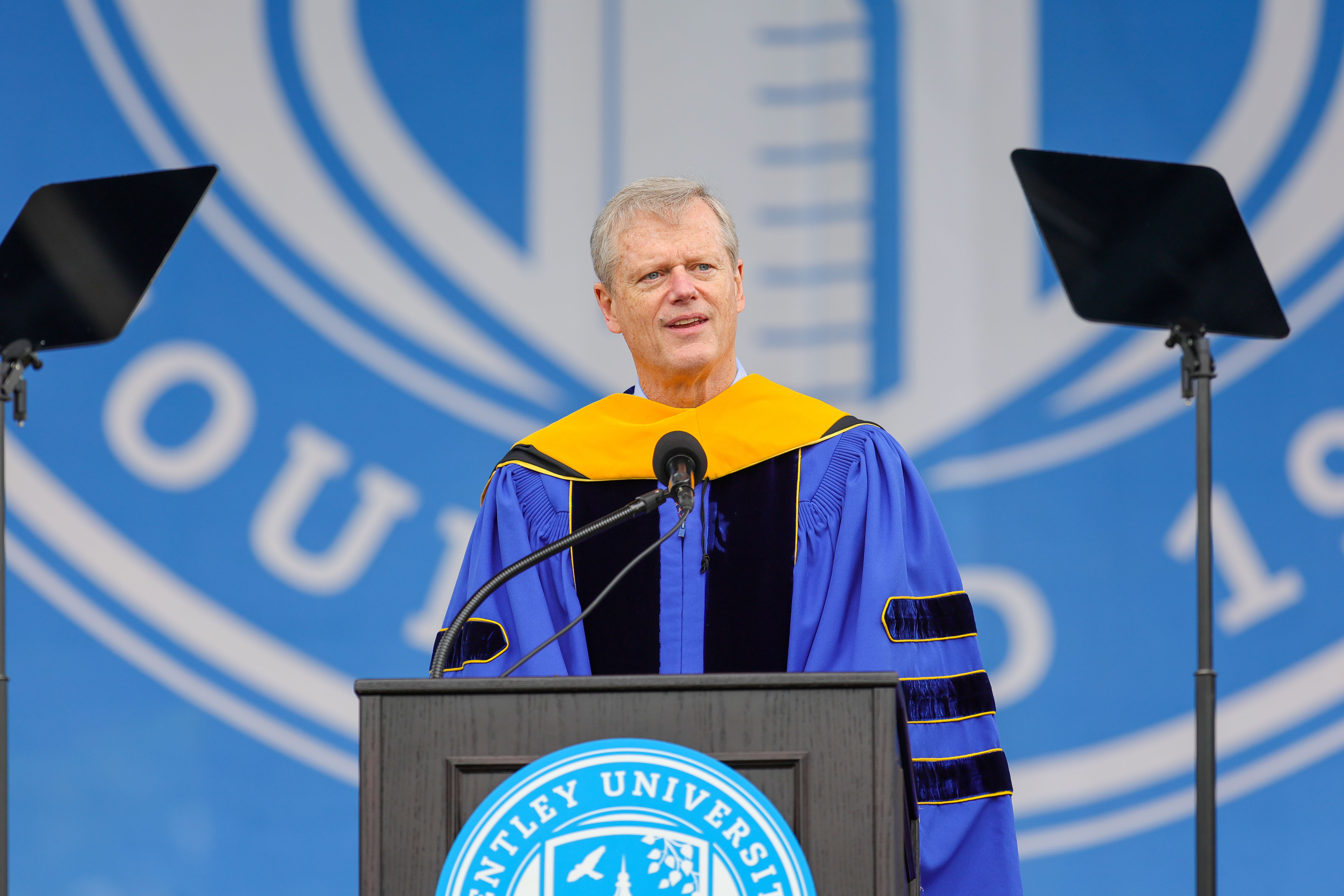 Charlie Baker speaks at a podium with the Bentley University logo behind him
