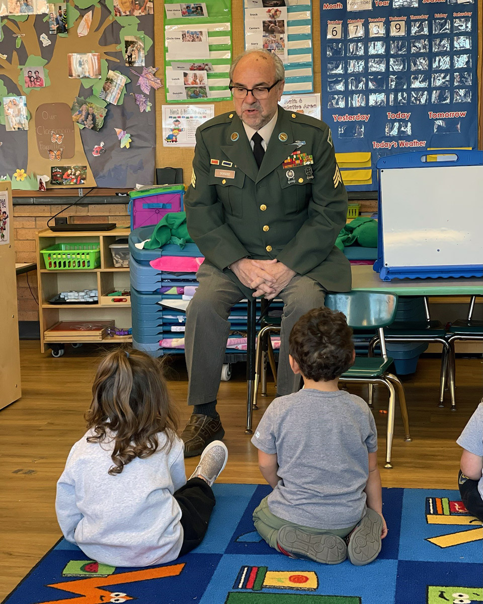 Paul Donahe poses with young students in a classroom