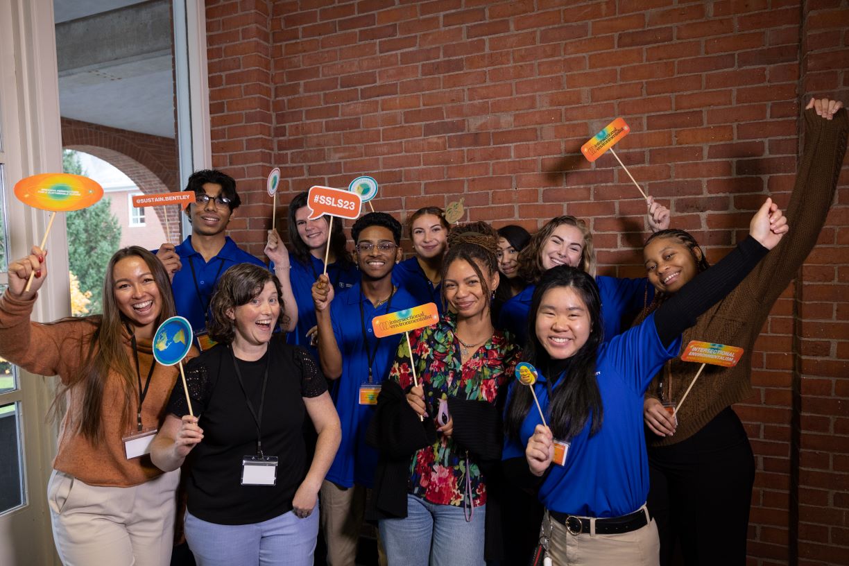 Leah Thomas and attendees gather on stage at the Sustainability Student Leaders Symposium at Bentley