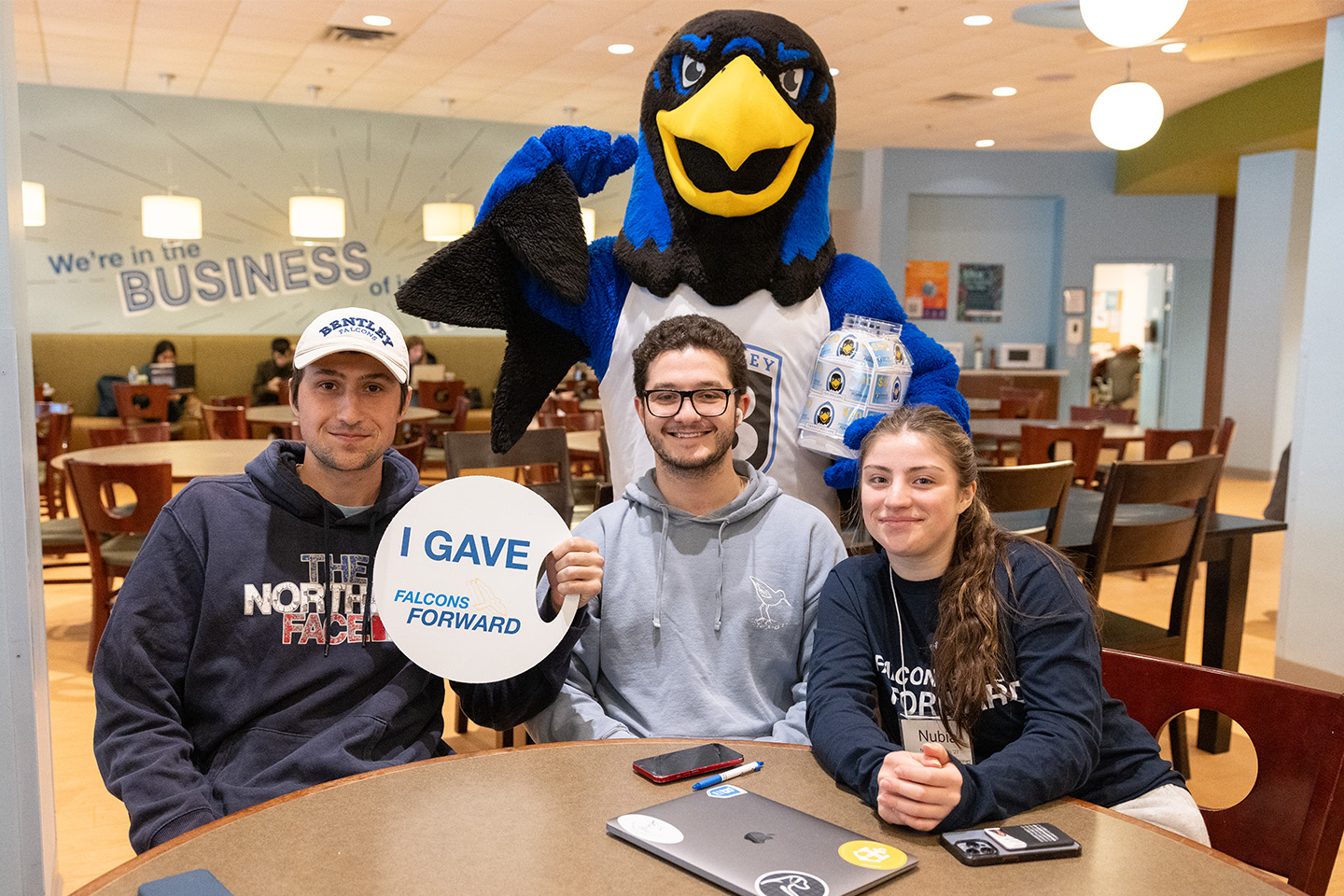 Flex poses with three students, one holding a sign that reads I Gave