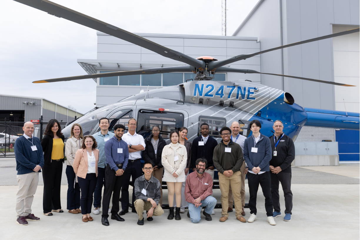Bentley students, faculty and staff pose in front of a helicopter with Boston MedFlight employees.