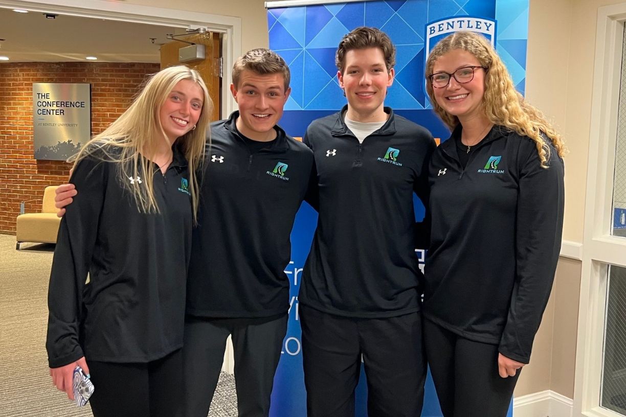 Four Bentley students pose with their arms around each other's shoulders.