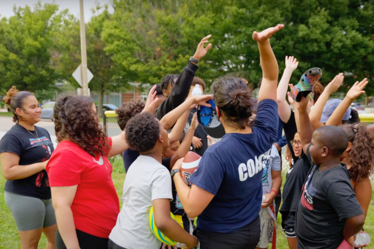 Coaches and students from the Doc Wayne program gather for a group high five