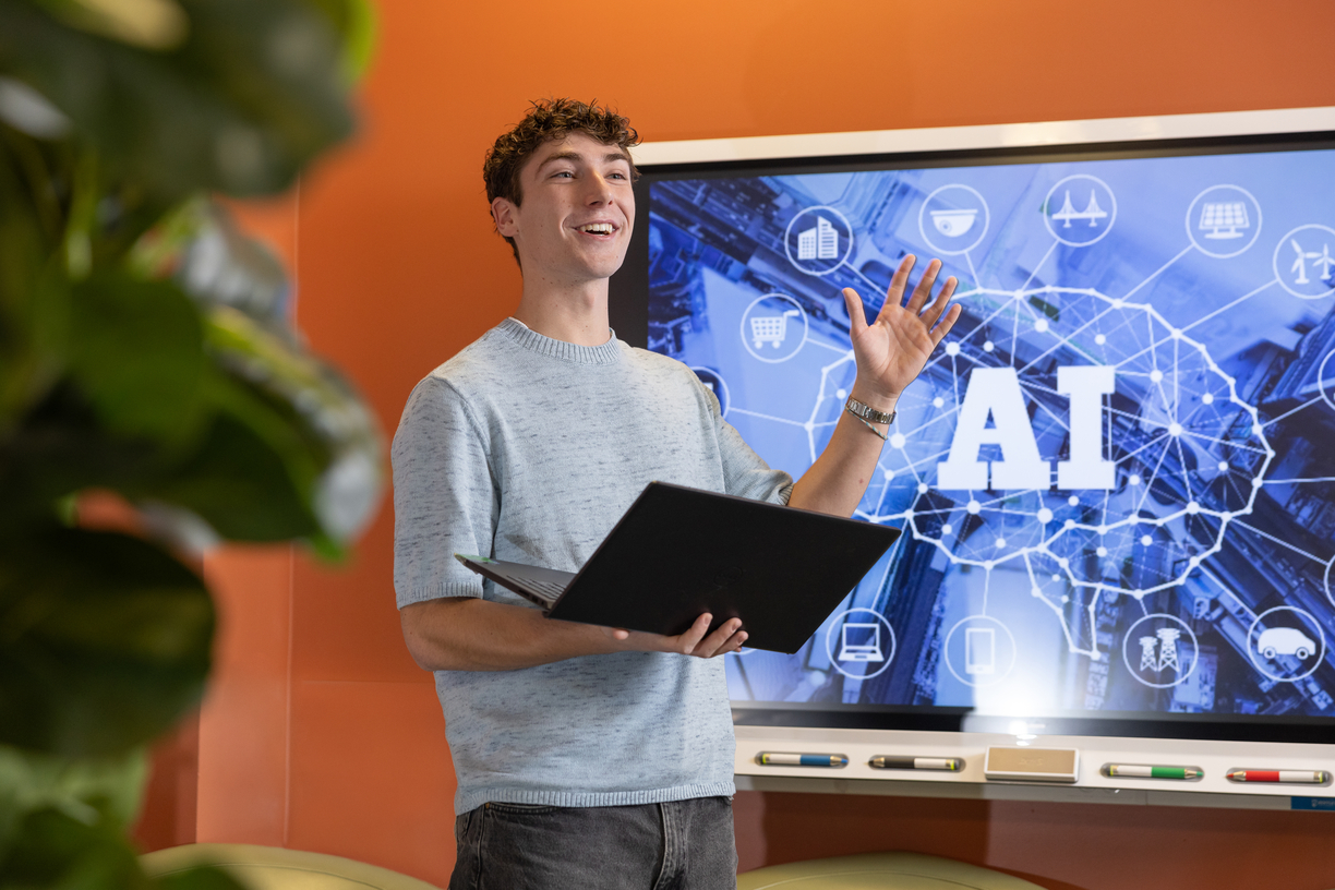 Bentley University student Aidan Griffith standing in front of a screen with an AI image in the CIS Sandbox 