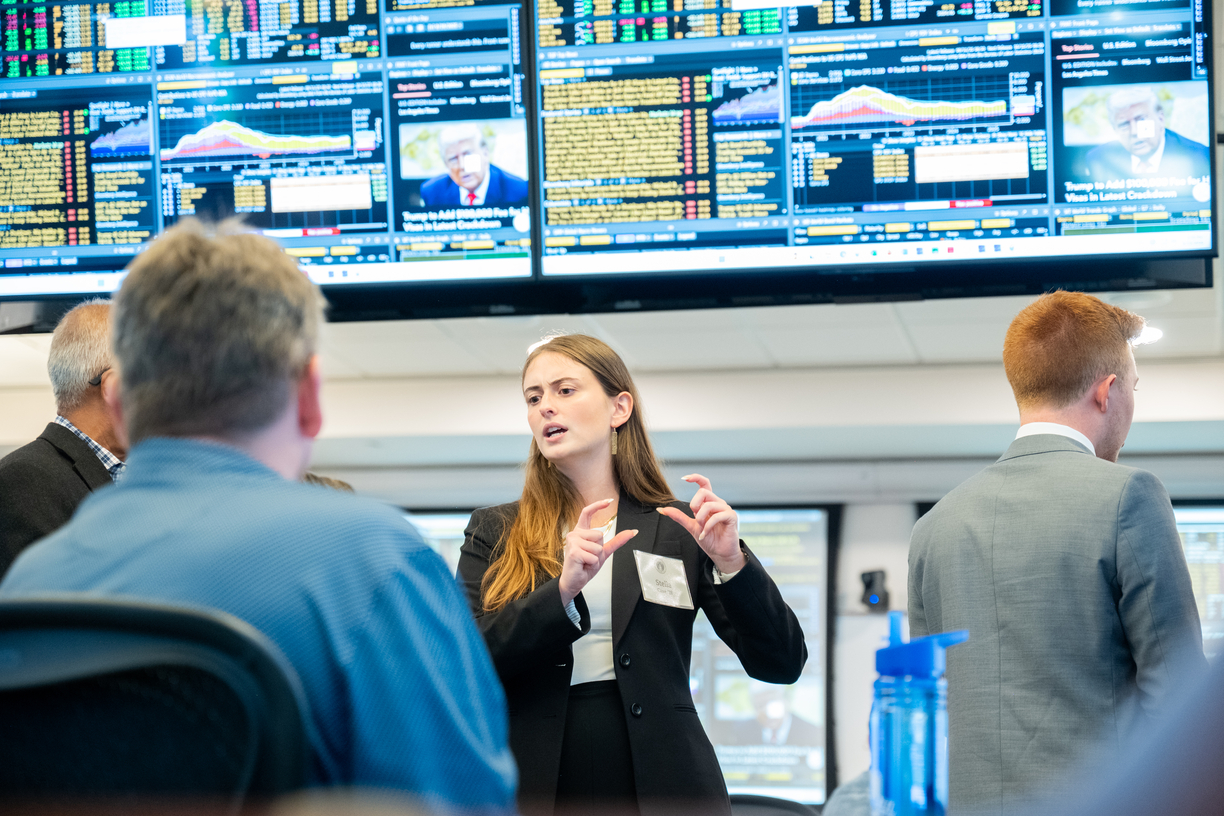 Female graduate student dressed in professional attire lectures adult learners in a high-tech business lab 
