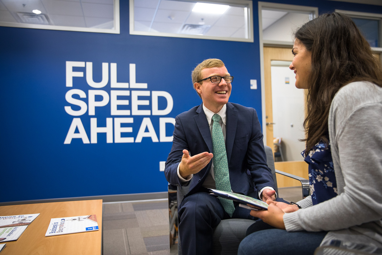 Photo of two students, one in a suit, talking