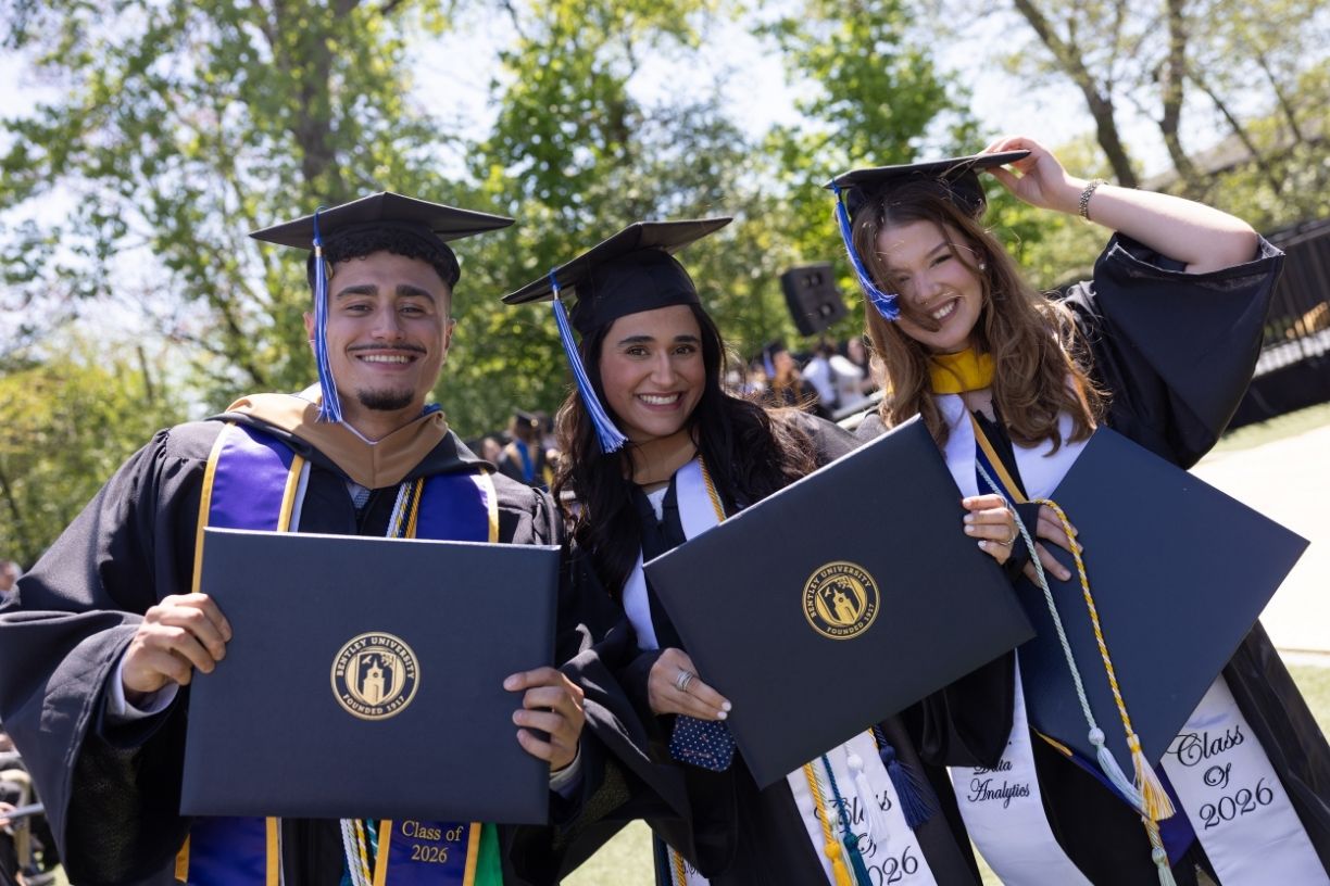 Friends from the Bentley Class of 2026 poses with their diplomas at Commencement ceremonies