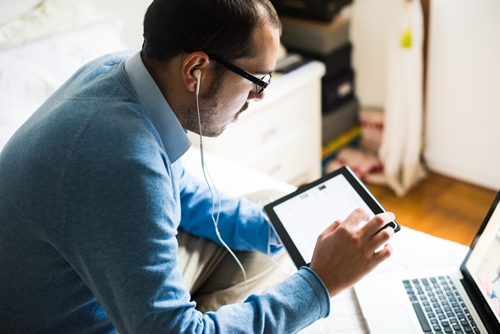 man using ipad and laptop