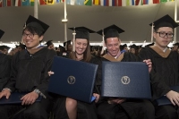 Students with diplomas in caps and gowns