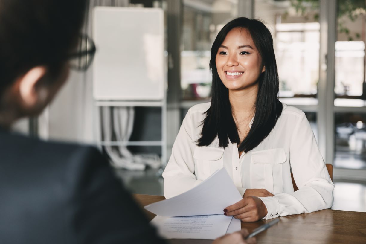 Woman holding paper sitting across from an interviewer at a table