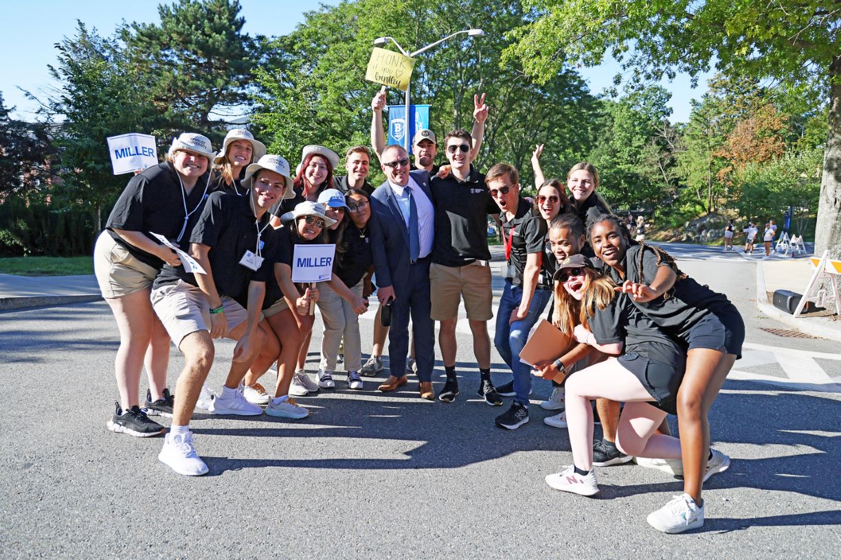 A group of Bentley orientation leaders wearing black t-shirts and holding signs to welcome the Class of 2026.