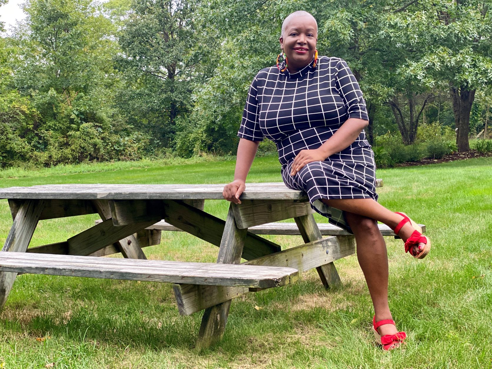 Elaine Dickson MBA '98 leaning against picnic table in black and white dress