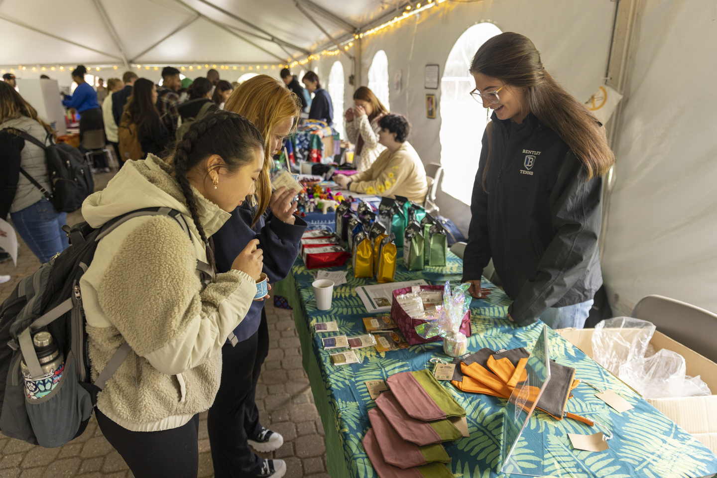 Bentley students browse colorful fabric products on a table at the fair trade fair