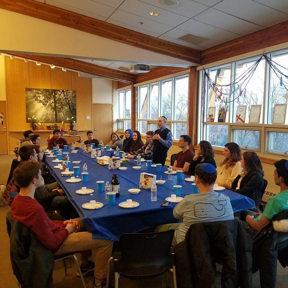 A group of people gather at a table in the Sacred Space for a seder. 