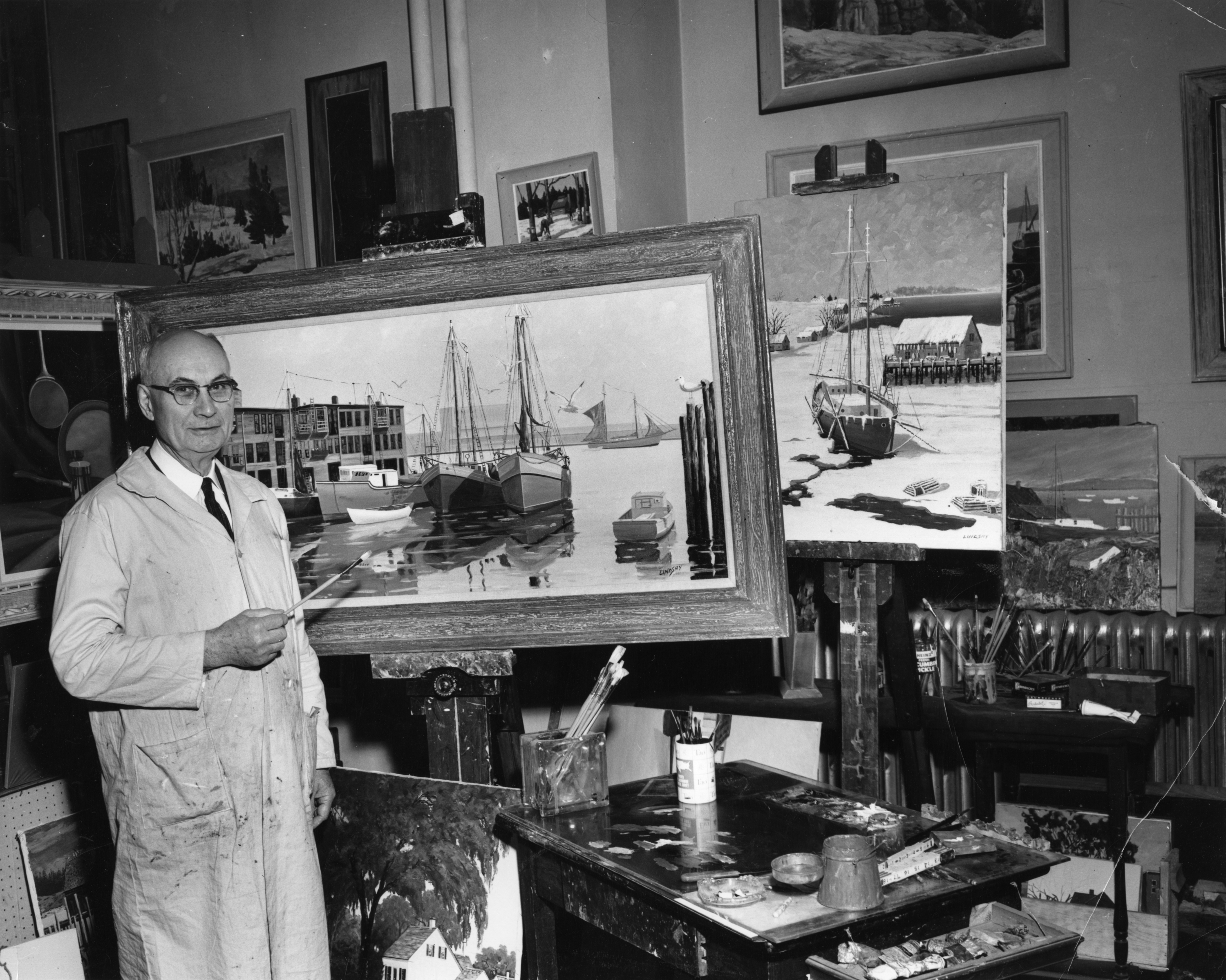 Maurice Lindsay in his art studio with paintings on easels in background