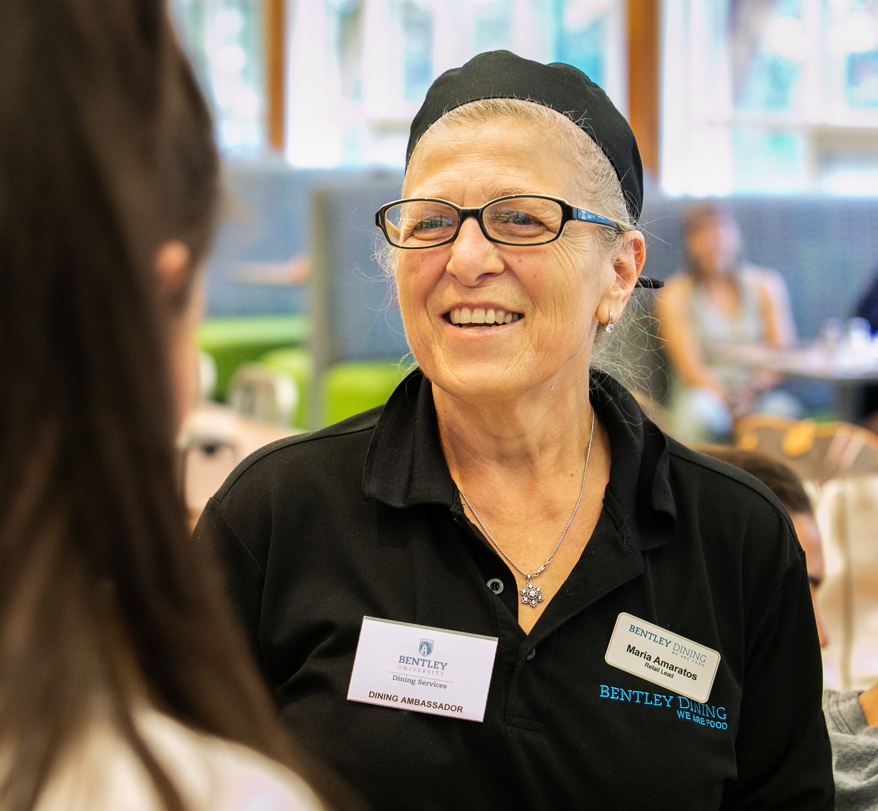 Maria Amaratos, a Dining ​Ambassador,                chats with a student in the 921.