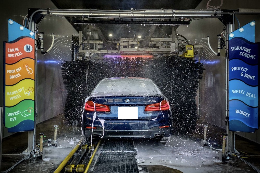 Photo of SUV entering car wash, with clear, colorful signage indicating what customers need to do: Place car in neutral; take foot off brake; remove hands from steering wheel; turn off windshield wipers.