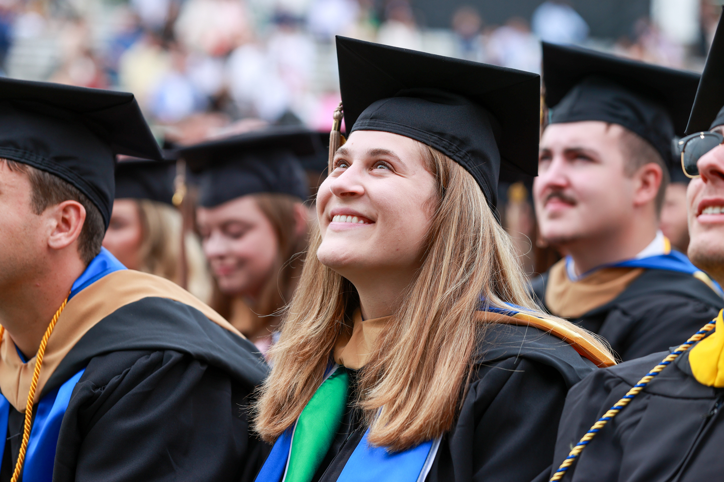 Bentley Class of 2023 graduate in regalia looking up and smiling