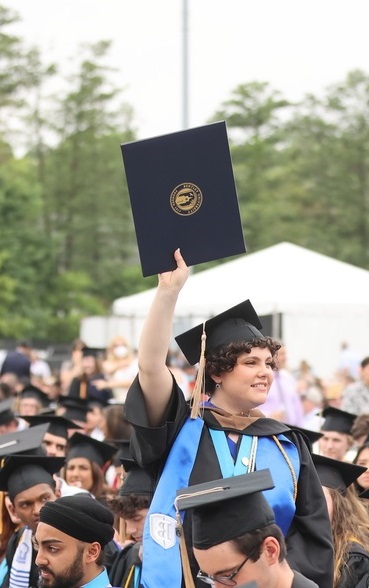 Bentley University student with her diploma in the air