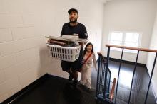 Student walking up stairs carrying laundry basket