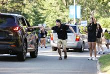Bentley orientation leader high-fives a student in a car on move-in day
