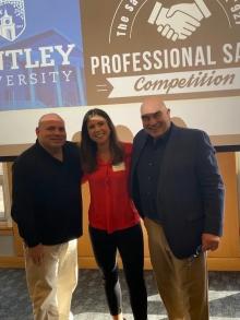 2 men and a woman in front of a Bentley sign