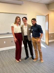 3 people standing in front of a white board