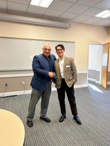 Two men facing forward shaking hands