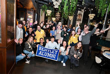 Group of alumni posing with banner that reads Bentley Alumni