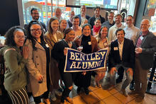 Group of alumni posing with banner that reads Bentley Alumni