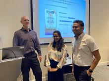 Three people posing for a picture in front of a screen.