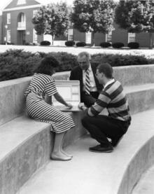 students and faculty sitting outside Adamian with computer
