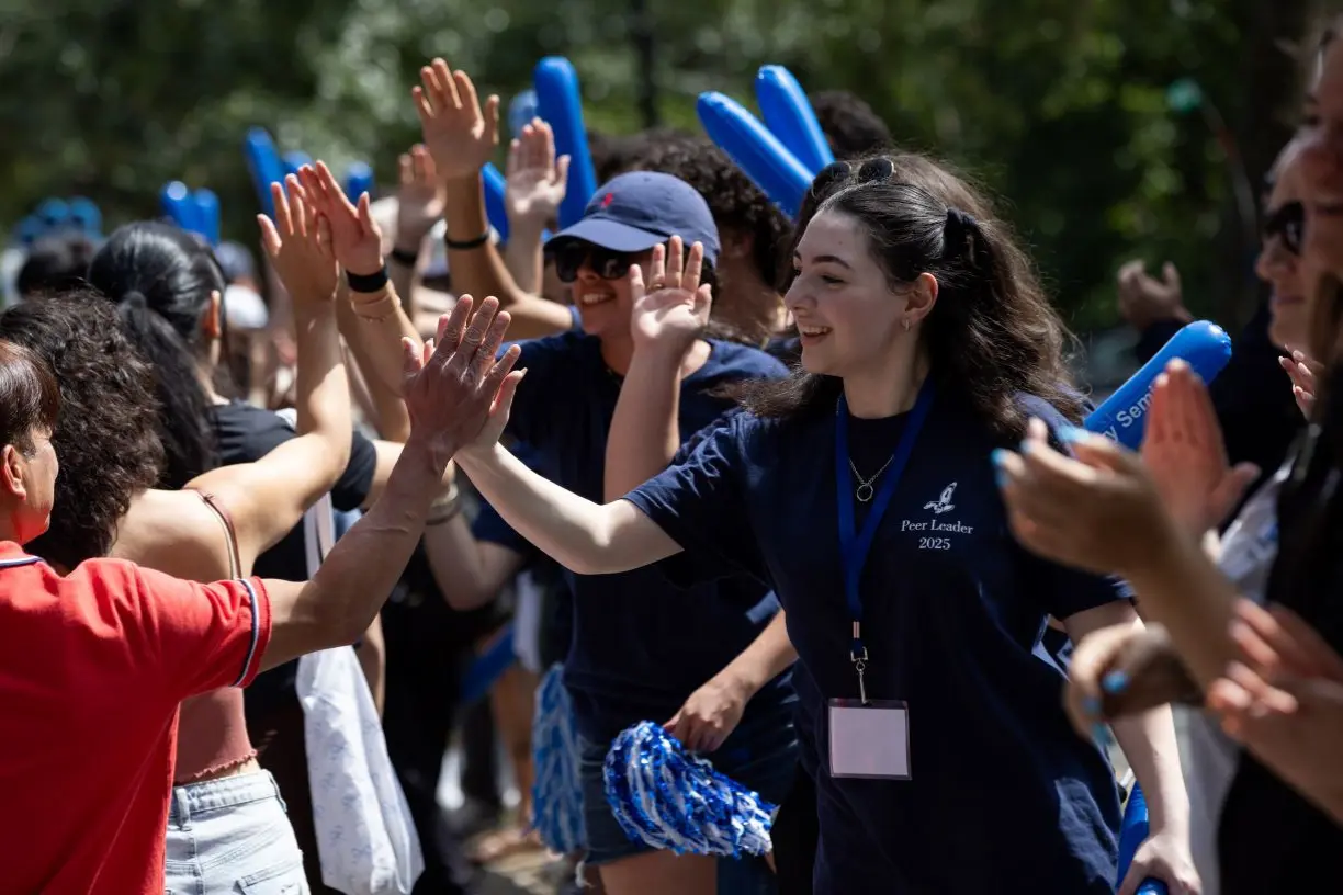 Bentley orientation leaders and volunteers welcoming new Bentley Class of 2029 students with high fives during move-in day
