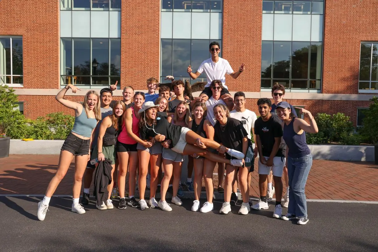 Ava Movsessian '26 poses with fellow Bentley orientation leaders in front of the iconic falcon statue on campus
