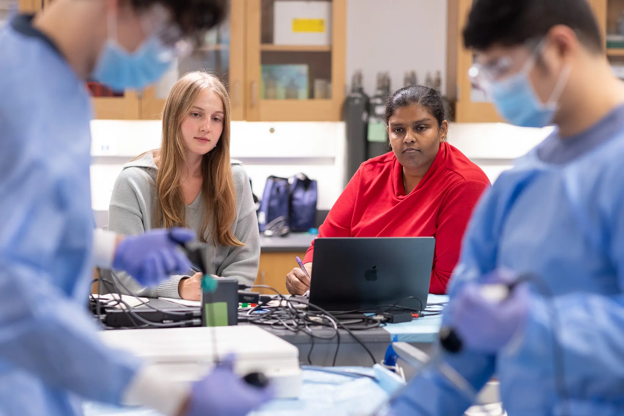 Bentley User Experience Center consultants Olivia Boardman, MSHFID ’26 and Ramya Mahendran, MSHFID ’25 observe Andrew Hahn, MSHFID ’25 (front left) and Ying Lung Kwan, MSHFID ’25 as they prepare surgical instruments for FDA clearance testing.
