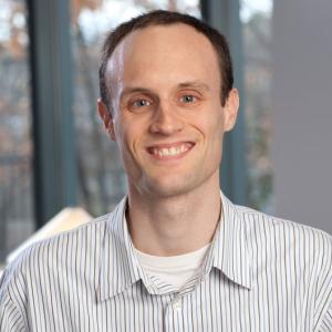 Headshot of professor Nathan Cater, wearing a striped Oxford shirt