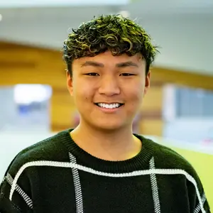 Alex Kim smiling wearing black and white sweater